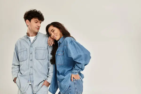 A stylish couple shows off trendy denim outfits with fun expressions in a modern studio. — Stock Photo