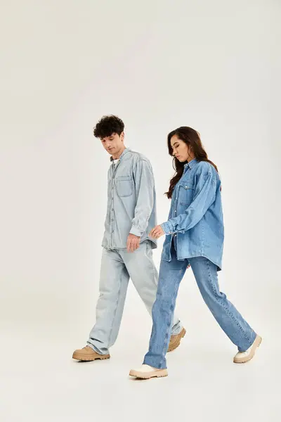 Two stylish people walk together, flaunting their trendy denim in a chic setting. — Stock Photo