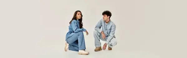 Young individuals exhibit fashionable denim outfits in a contemporary studio space. — Stock Photo