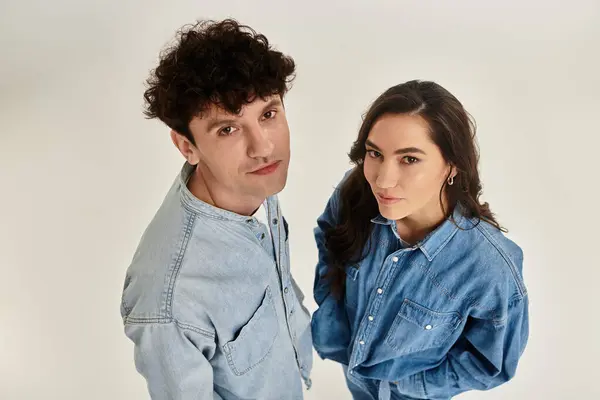 Les jeunes individus branchés posent avec confiance dans un studio lumineux, mettant en valeur leur style denim. — Photo de stock