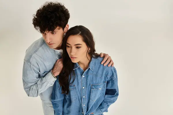 Two stylish individuals showcase trendy denim outfits, embodying youthful fashion in a bright space. — Stock Photo