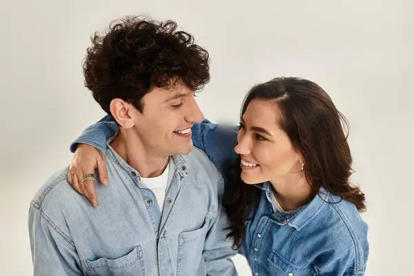 Happy young couple smiles at each other, flaunting their stylish denim outfits playfully. — Stock Photo