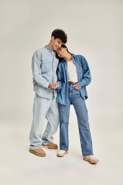 Young couple displays trendy denim fashion, radiating joy and connection in a stylish studio. — Stock Photo