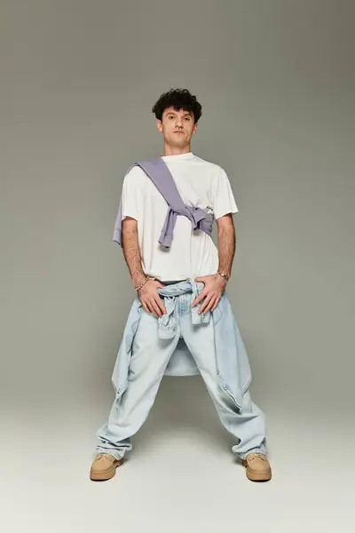 A young individual poses confidently in trendy attire, exuding a stylish vibe in soft lighting. — Stock Photo