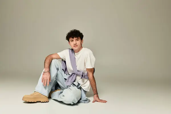 A young man poses stylishly and relaxed in a chic, minimalist setting. — Stock Photo