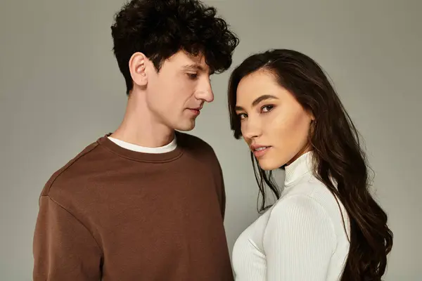 A young couple poses in trendy outfits with stylish looks against a neutral background. — Stock Photo