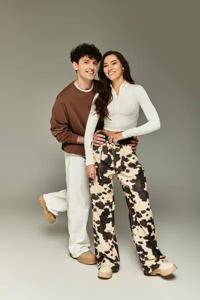 A stylish young couple smiles together, showcasing their outfits and playful charm. — Stock Photo
