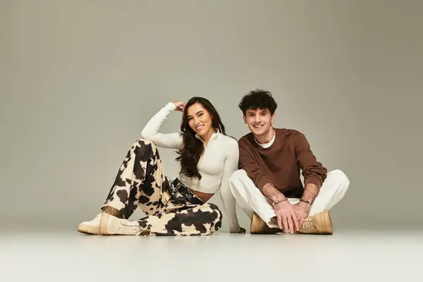 Two fashionable young individuals pose playfully on the floor, exuding confidence and style. — Stock Photo