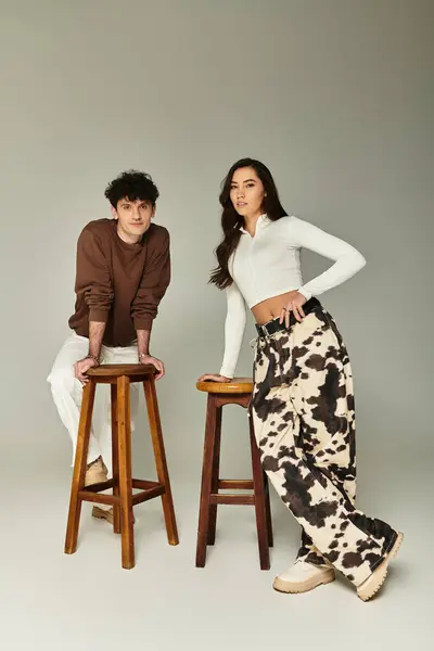 Due persone alla moda sugli sgabelli espongono i loro abiti alla moda in uno studio chic. — Foto stock