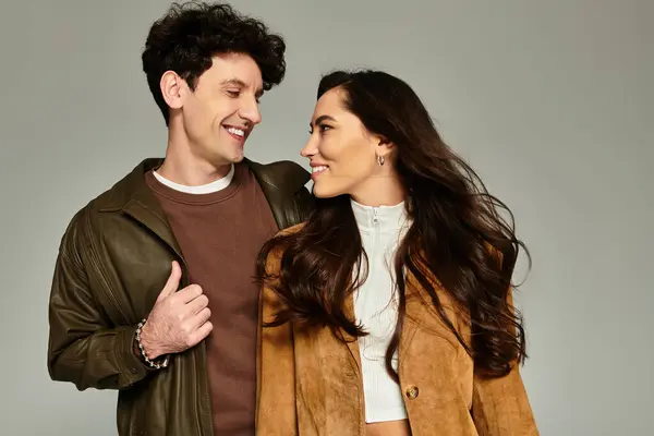 Young couple dressed in fashionable attire share smiles and connection in a modern setting. — Stock Photo