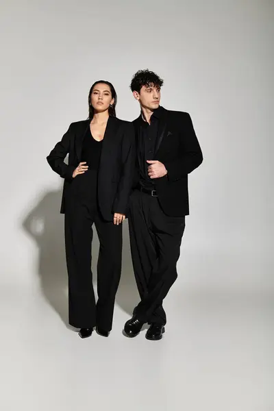 A young couple radiates elegance in matching black outfits against a neutral background. — Stock Photo