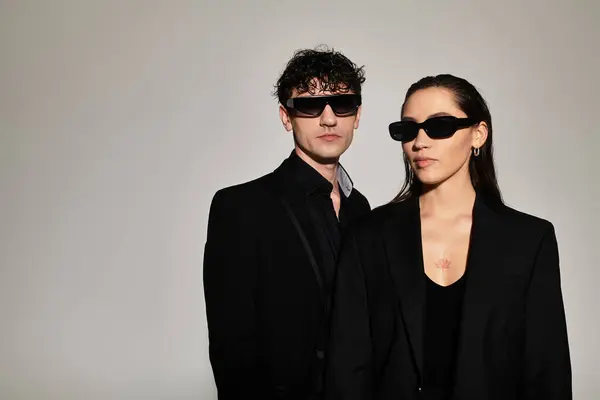 Young couple stands confidently in sleek black attire, embodying contemporary elegance and style. — Stock Photo
