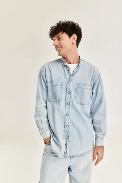 A young man dressed in a light denim shirt displays confidence and style in a contemporary setting. — Stock Photo