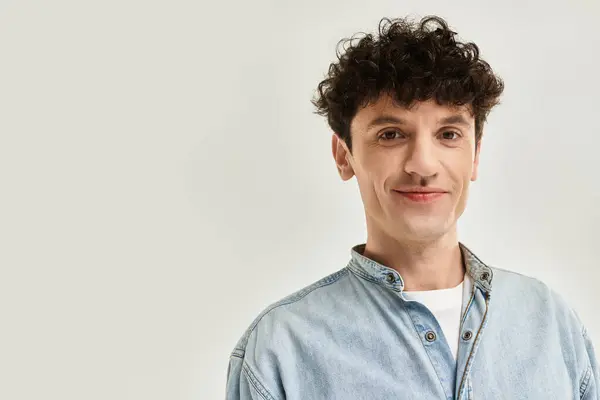 A young man exudes style and confidence with his trendy denim attire in a minimalist space. — Stock Photo