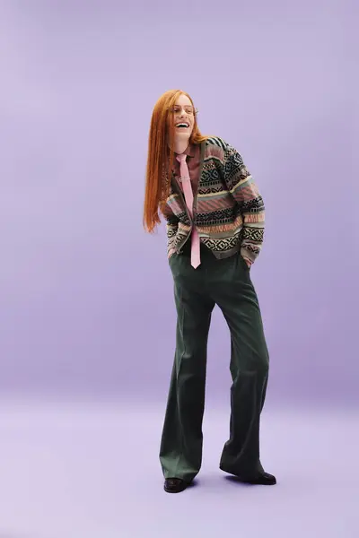 A young queer person with long red hair confidently poses in a trendy outfit on a pastel backdrop. — Stock Photo
