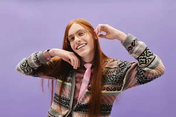 A stylish young man with long red hair poses playfully against a chic purple backdrop. — Stock Photo