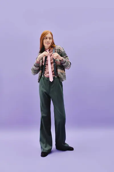 A young queer man with long red hair confidently models a trendy outfit in a vibrant setting. — Stock Photo