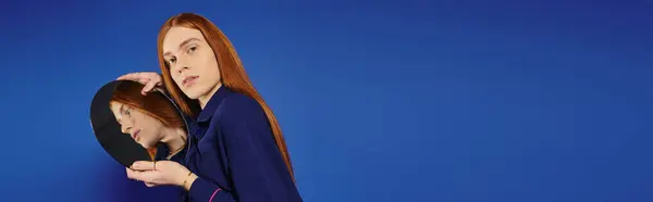 Young queer man showcases his long red hair and fashion sense against a bold blue backdrop. — Stock Photo