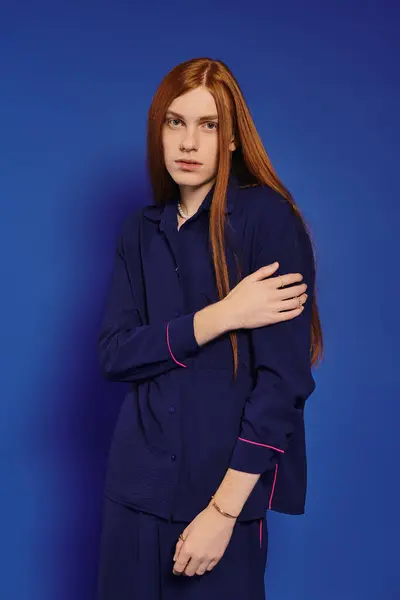 A young man with red hair poses in style against a vivid blue backdrop. — Stock Photo