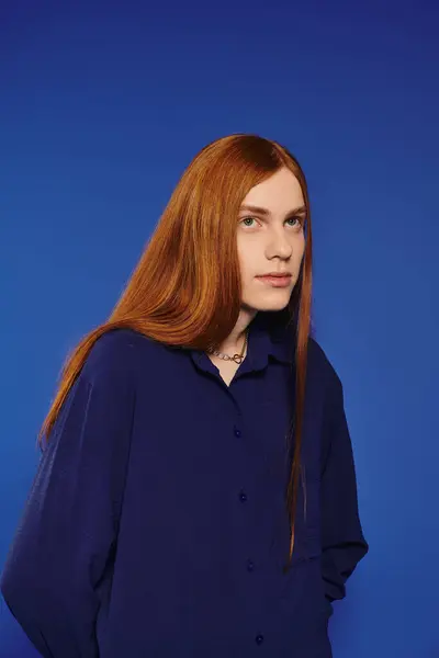 A young man with striking red hair confidently showcases his fashion in a modern scene. — Stock Photo