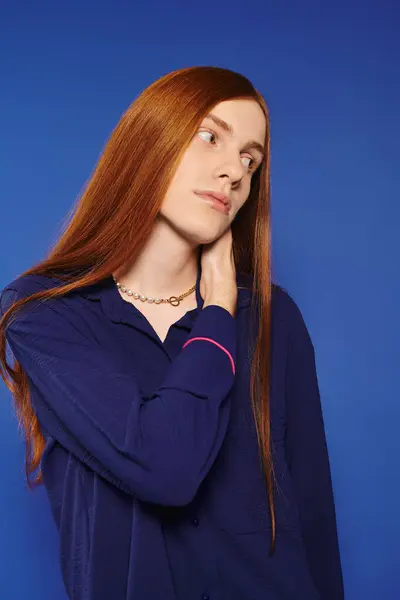A fashionable young man with long red hair stands confidently, showcasing his modern style. — Stock Photo