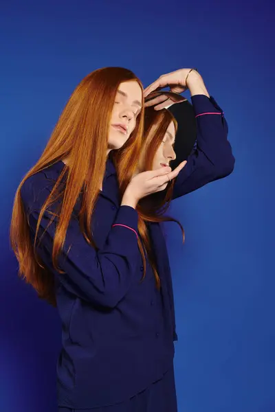 A young man with long red hair showcases his unique style in a modern setting with vibrant colors. — Stock Photo