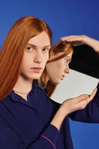 A young queer man with long red hair poses with a mirror, exploring identity. — Stock Photo