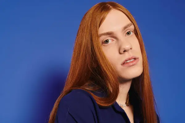 A stylish young queer man with long red hair embraces his self expression in this portrait. — Stock Photo