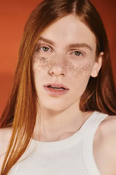 A stylish young person with long red hair and freckles shines in a vibrant setting. — Stock Photo