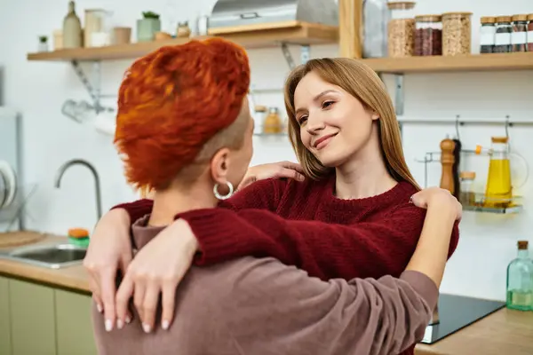 Two young women share a joyful embrace in a stylish apartment, radiating love and connection. — Stock Photo