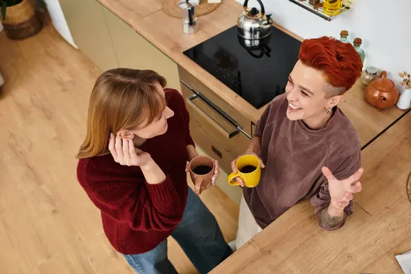 A joyful moment as a beautiful young couple shares coffee and stories in their stylish apartment. — Stock Photo