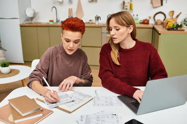 Two young women work together on a project in their cozy apartment, sharing moments of love. — Stock Photo