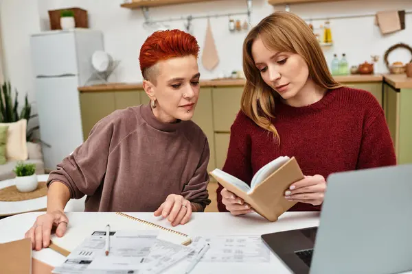 Due belle giovani donne godono il loro tempo insieme leggendo in un grazioso appartamento. — Foto stock