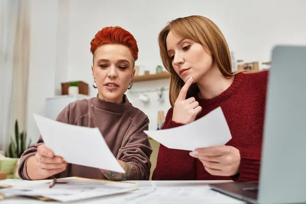 Due belle giovani donne condividono un momento di connessione durante la revisione dei documenti a casa. — Foto stock