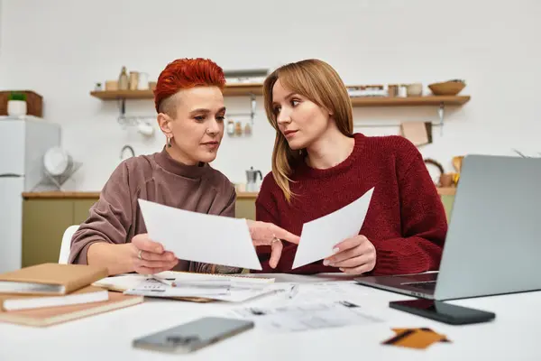 Due giovani donne condividono un momento di gioia durante la revisione dei documenti a casa. — Foto stock
