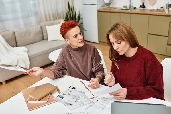 Two women share a moment in a stylish apartment, focusing on their plans, and family budget — Stock Photo