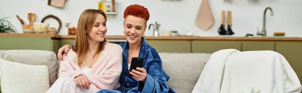 Deux belles femmes partagent le rire et l'amour tout en se relaxant sur leur canapé dans un espace élégant, bannière — Photo de stock