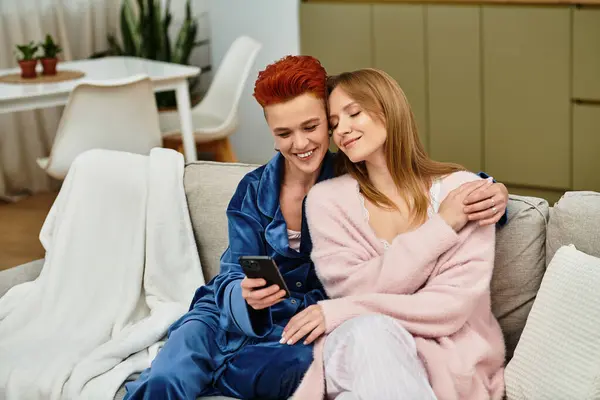 Dos hermosas mujeres jóvenes disfrutan de la compañía mientras se relajan en un acogedor sofá en casa. - foto de stock