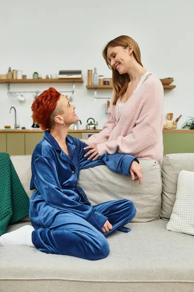 Dos mujeres jóvenes comparten un momento de alegría en su acogedor apartamento, irradiando amor y conexión. - foto de stock