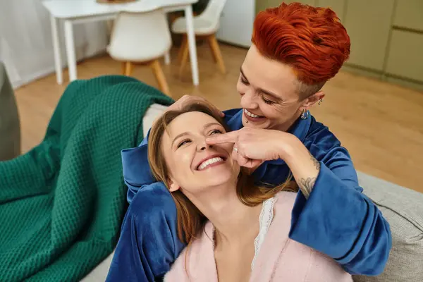 Two joyful women share a playful moment while relaxing in their cozy apartment together. — Stock Photo