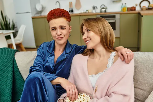 Two beautiful women share a playful moment while relaxing on their couch at home. — Stock Photo