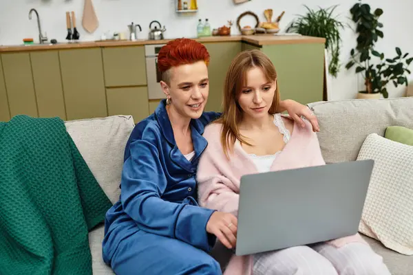 A beautiful young lesbian couple enjoys quality time together on a sofa, sharing laughter and love. — Stock Photo