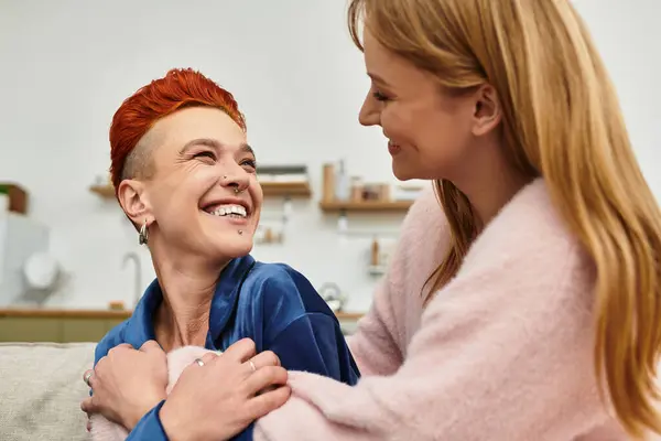Two young women laugh together, enjoying their intimate connection in a stylish home. — Stock Photo