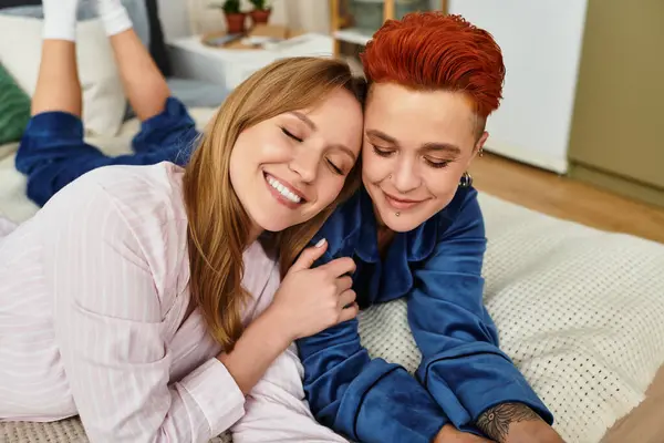 Two young women share tender moments on a cozy bed in their stylish bedroom, surrounded by warmth. — Stock Photo