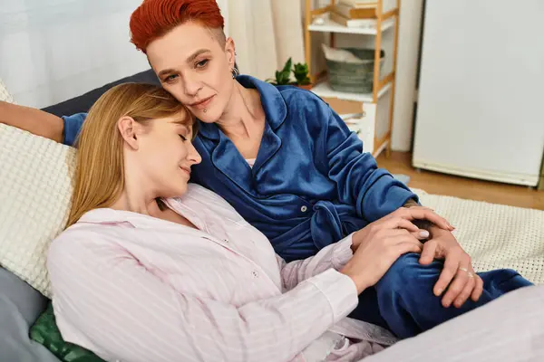 Two beautiful young women relax together in their stylish bedroom, enjoying each others company. — Stock Photo