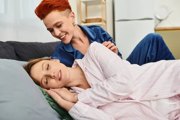 In a stylish bedroom, a beautiful young couple enjoys a tender moment as they embrace in bed. — Stock Photo
