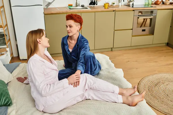 Two young women share a loving gaze while relaxing in their stylish bedroom, showcasing romance. — Stock Photo