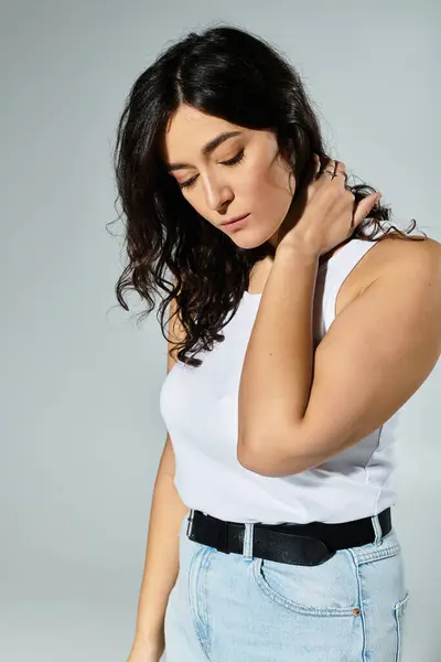 Joven y segura mujer de talla grande en una camiseta blanca posando en un ambiente de estudio. - foto de stock