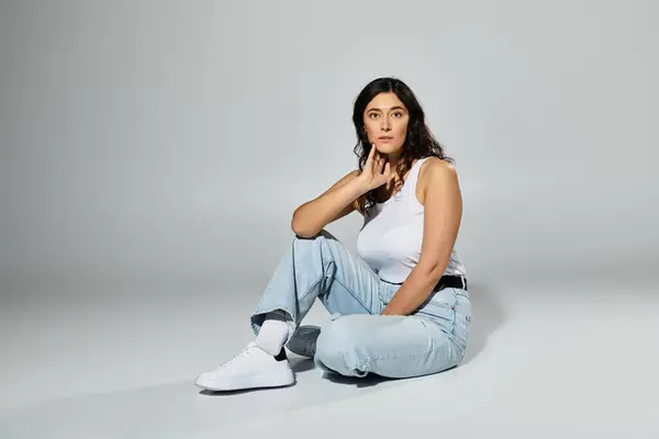 Plus size woman showcases confidence in stylish white tank top and casual jeans. — Stock Photo