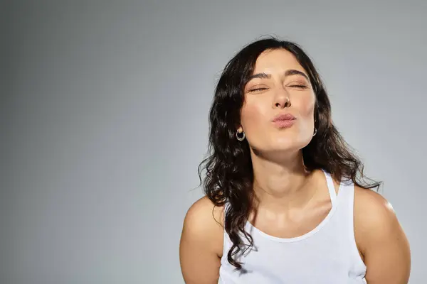 Gioioso bruna donna soffiando un bacio in un ambiente elegante studio. — Foto stock